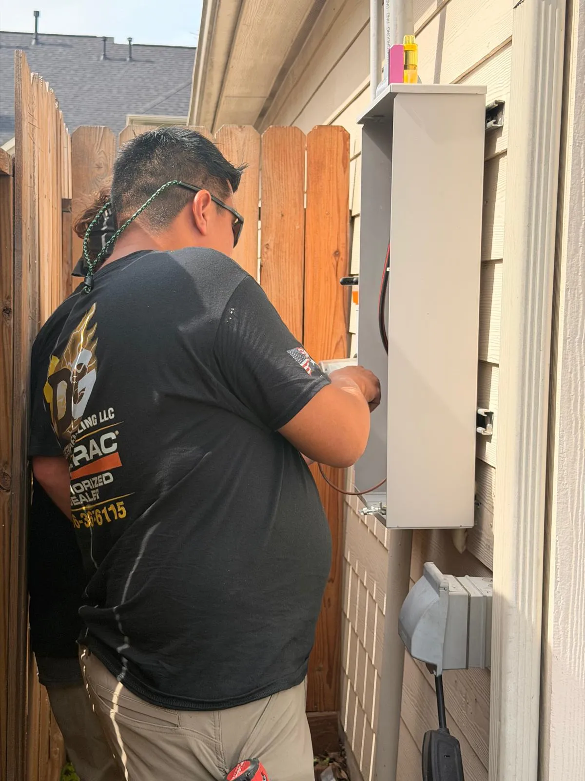 DG technician in Generac dealer uniform wiring an exterior transfer switch