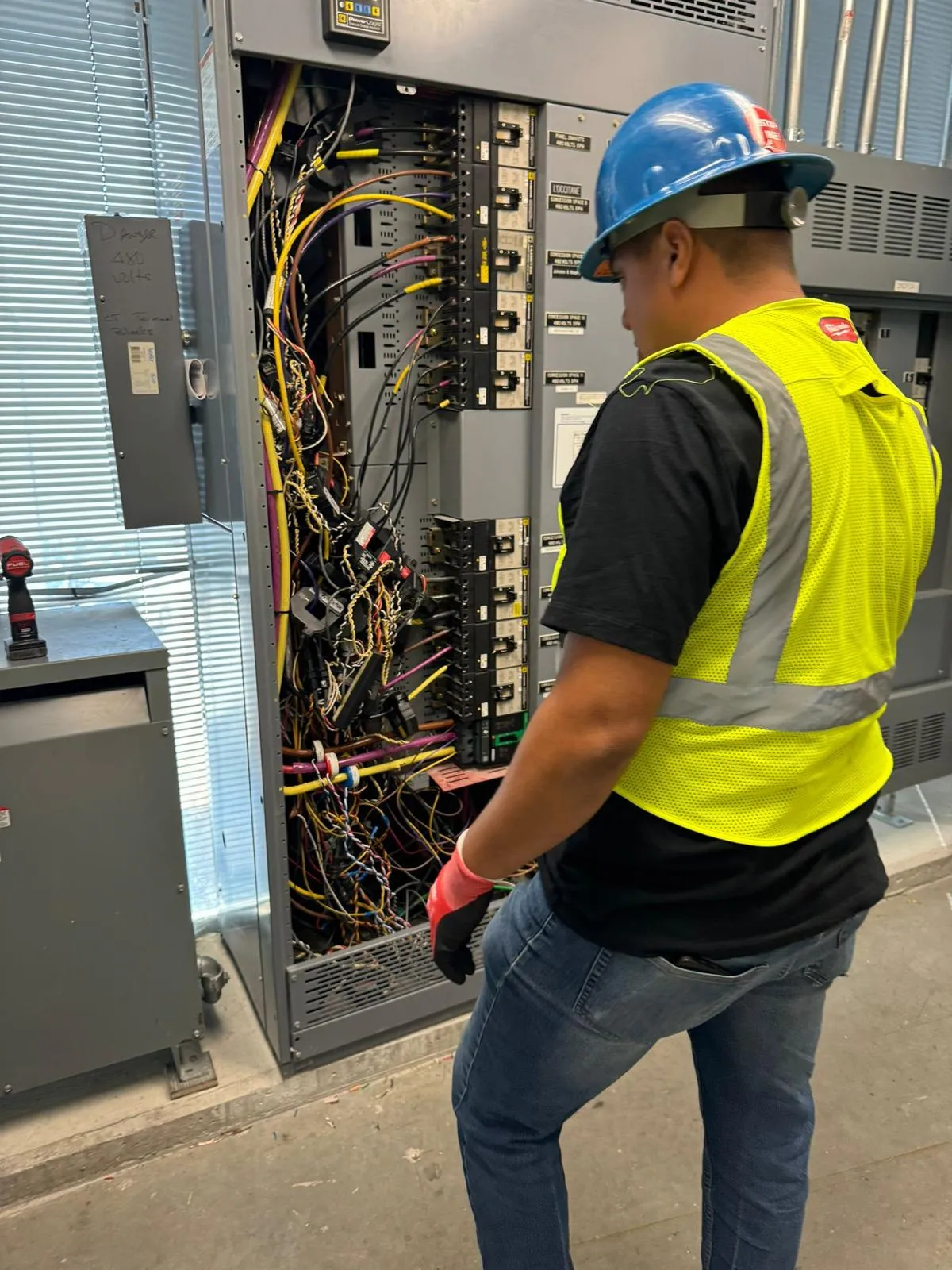 DG electrician in full PPE working on an open commercial switchboard