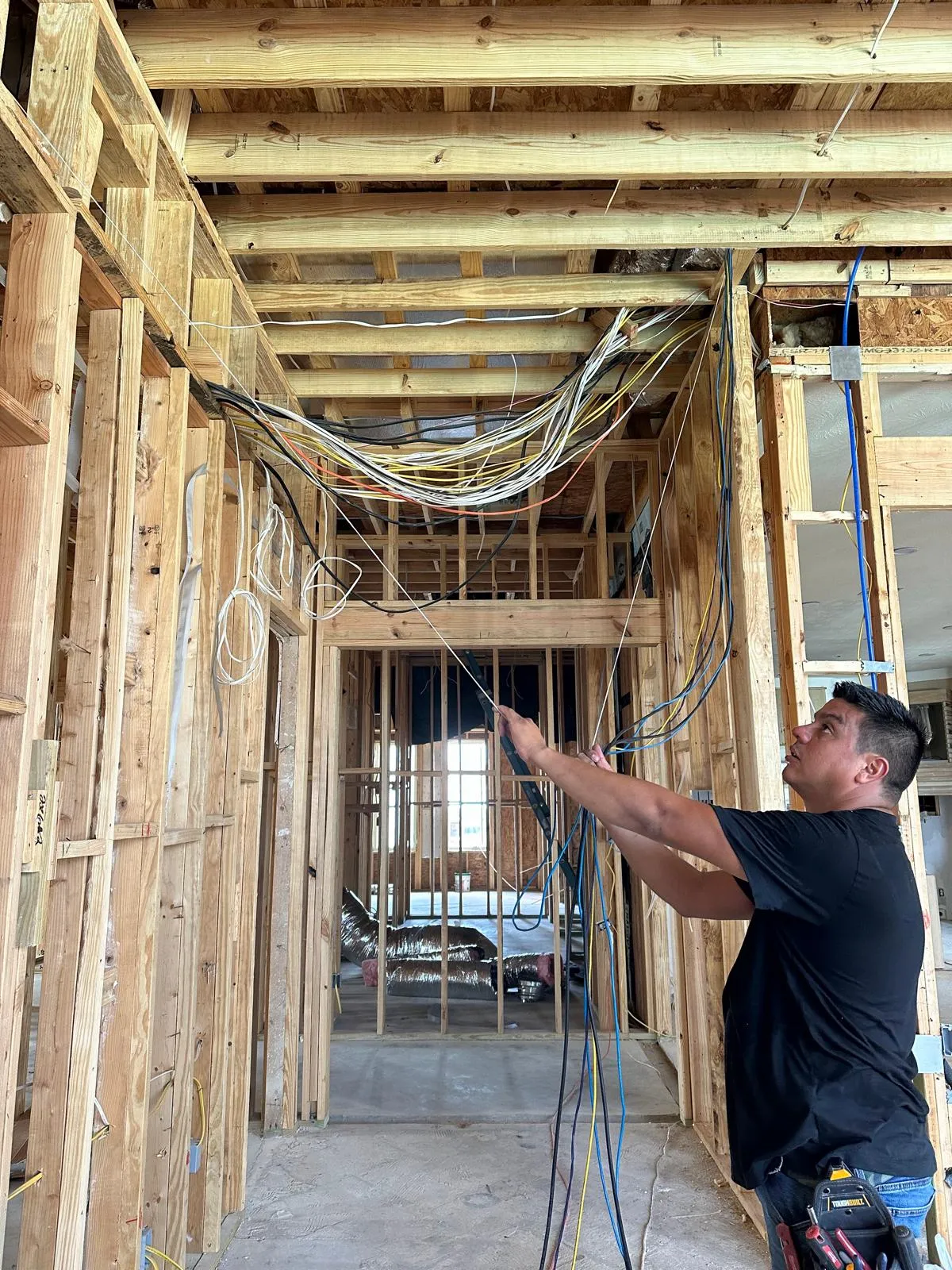 Electrician routing cables overhead during new-construction rough-in