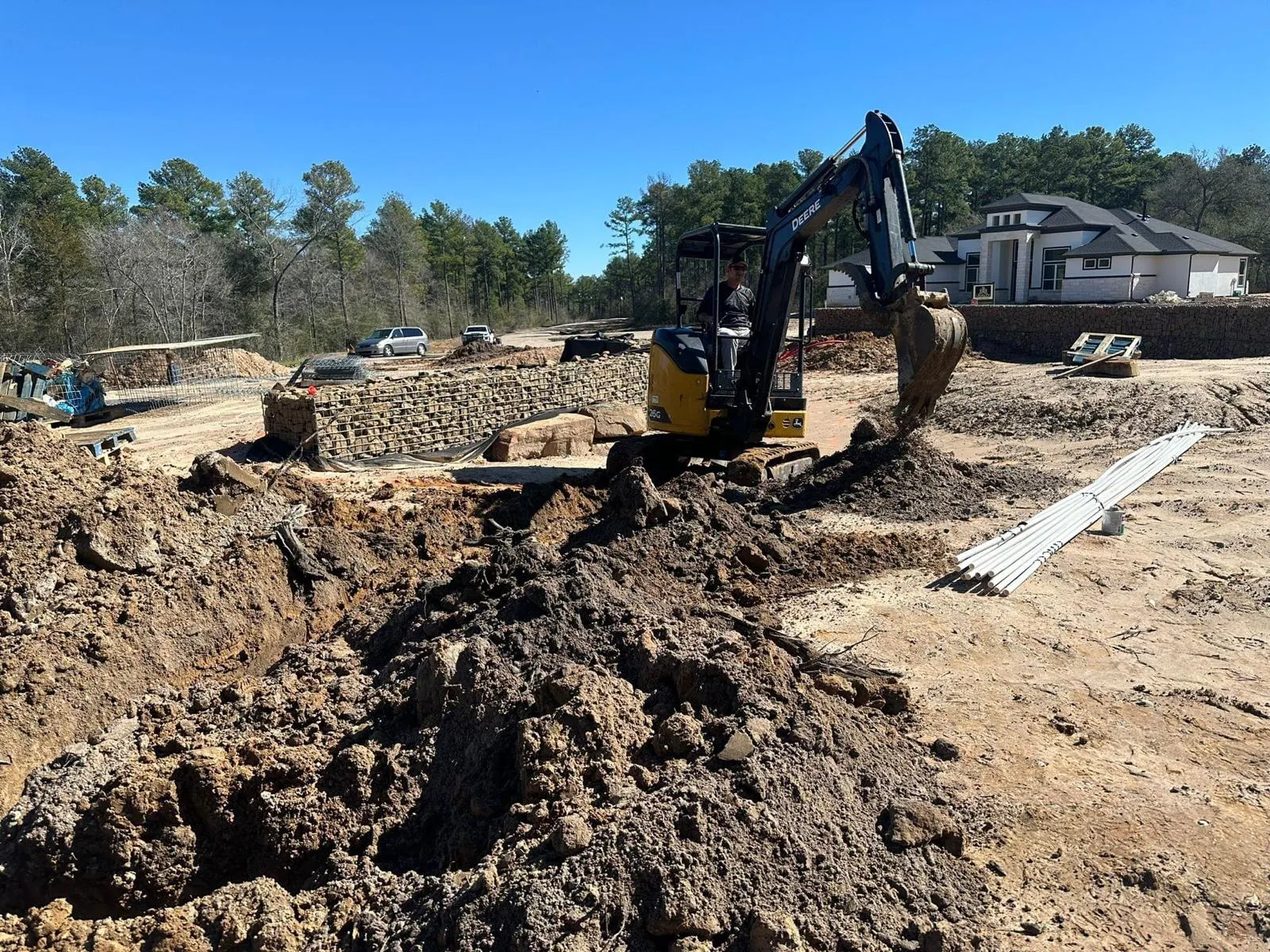 Mini excavator digging utility trenches for conduit at a new construction site