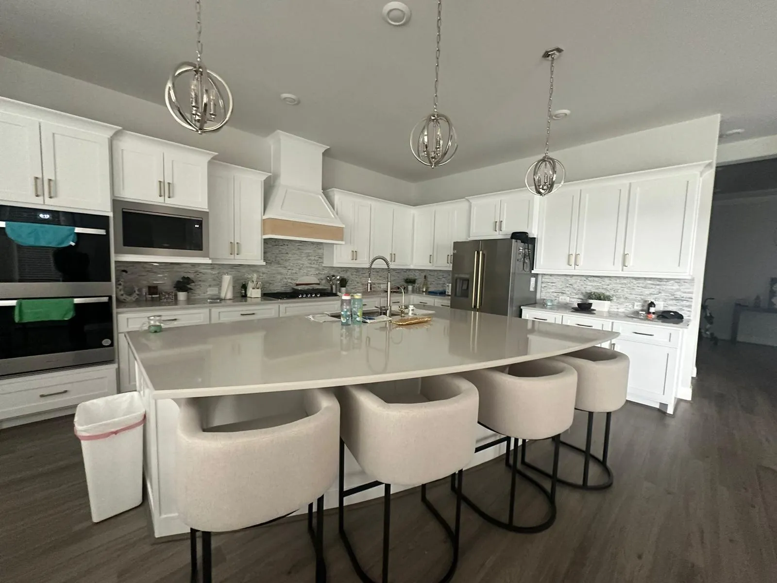 Finished white kitchen remodel with large quartz island and pendant lights
