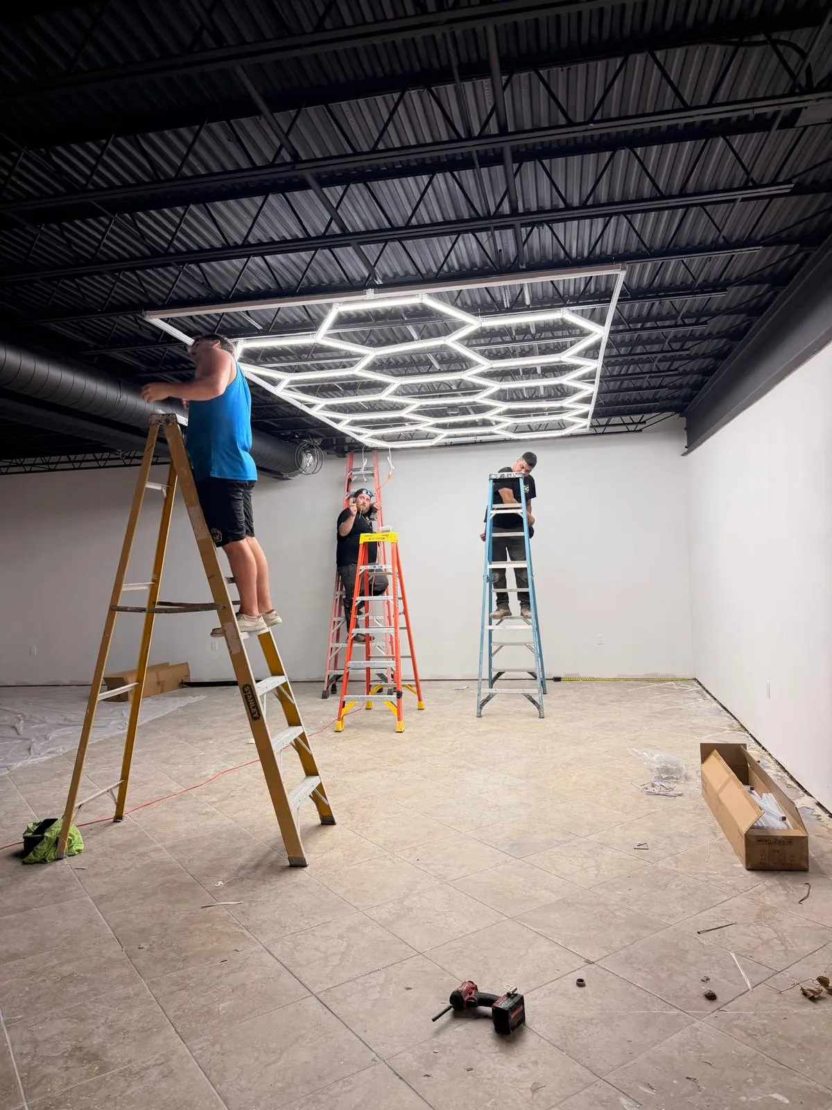 DG team on ladders installing a custom hexagon LED grid in a retail space