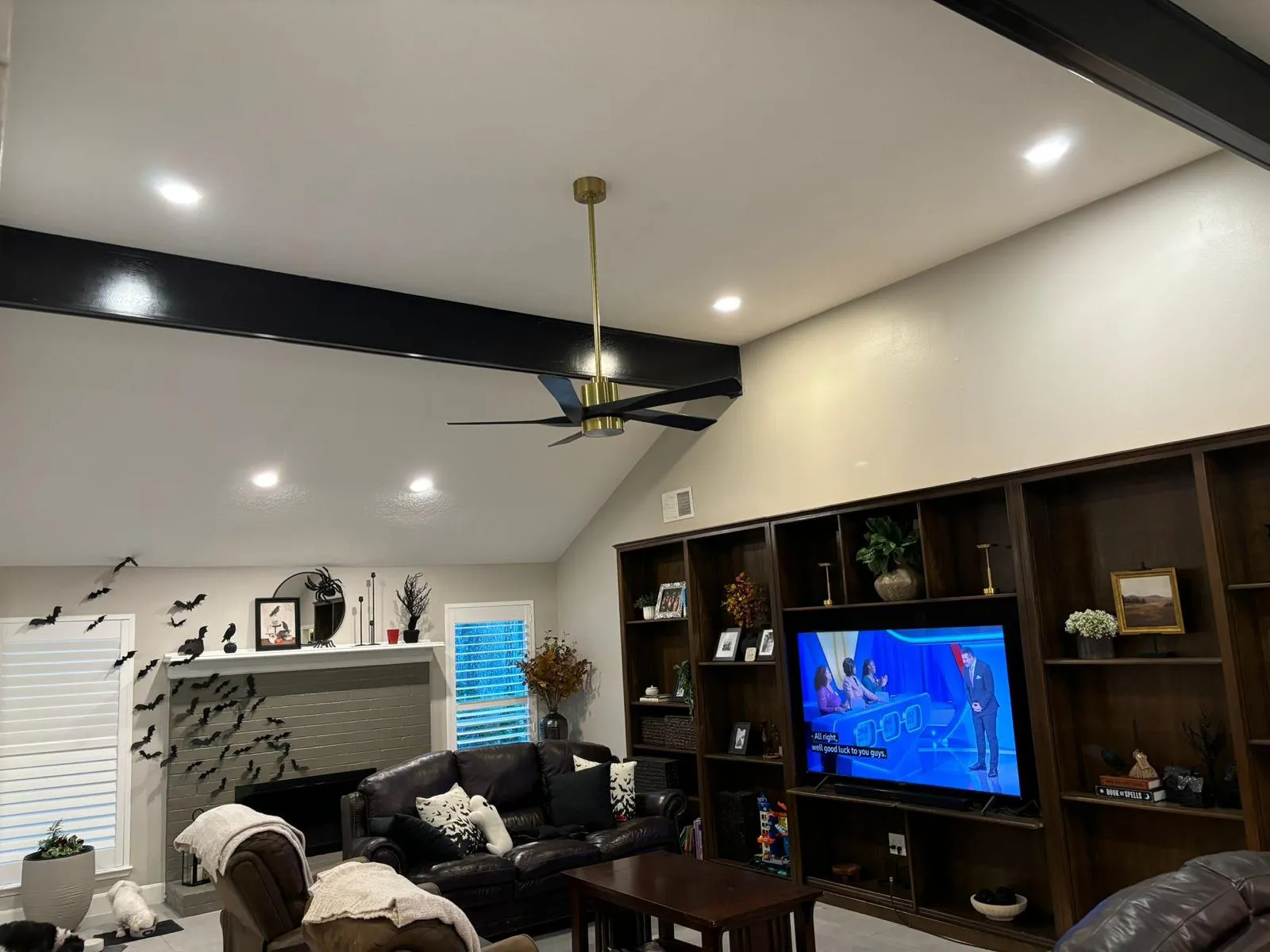 Vaulted living room with black beams, brass ceiling fan and recessed lighting