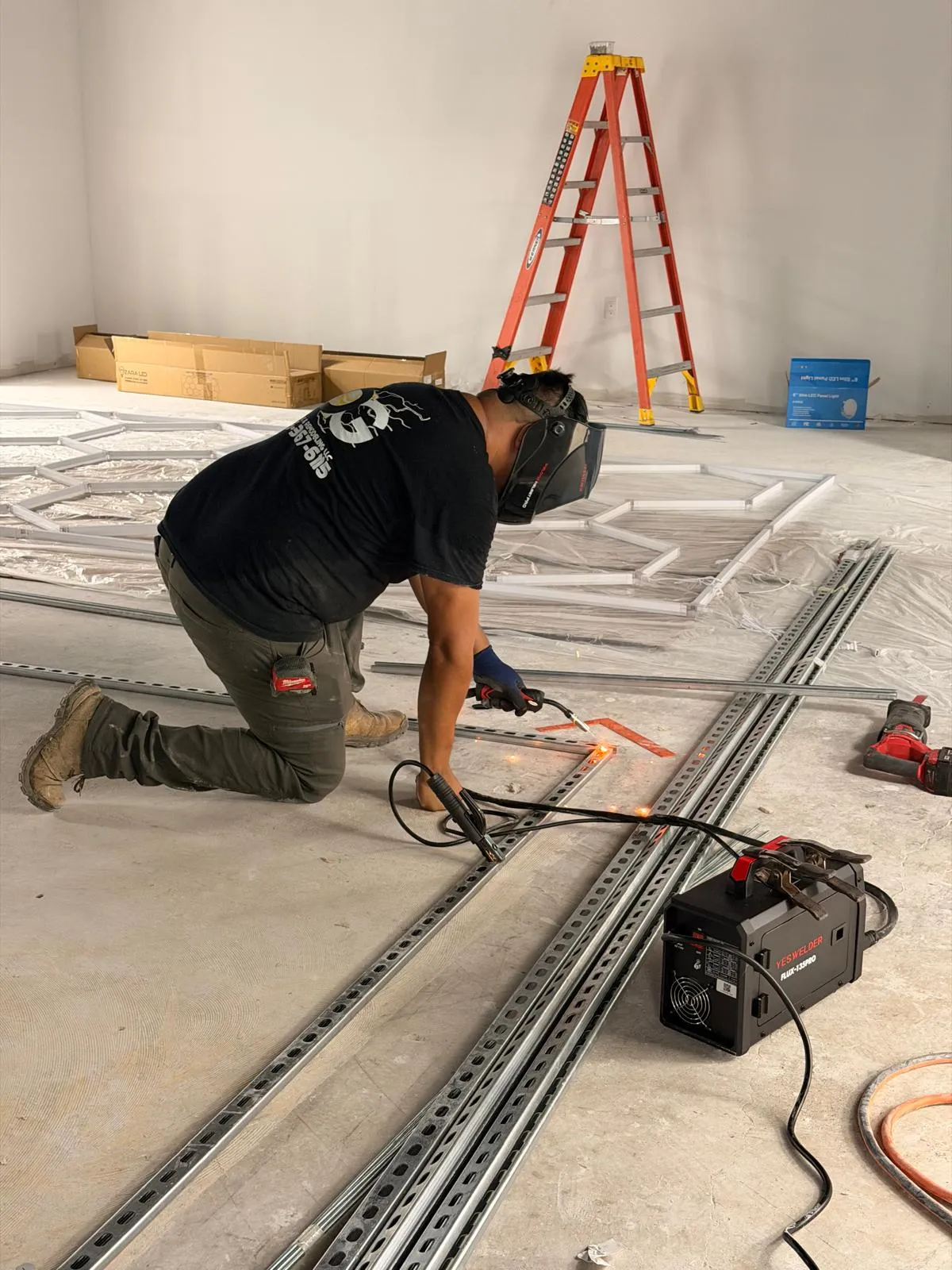 Welder fabricating a custom steel frame for a hexagon LED installation